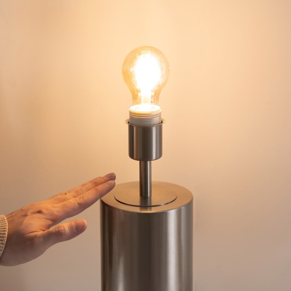 An image showing a person's hand as they reach out to touch a touch table lamp and turn it on