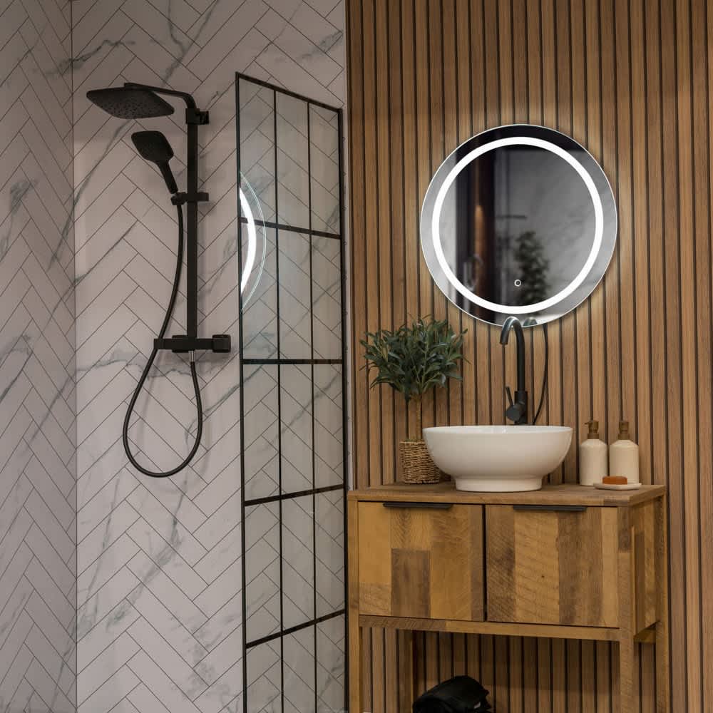Modern bathroom with illuminated round LED mirror, wooden vanity unit and black shower fittings