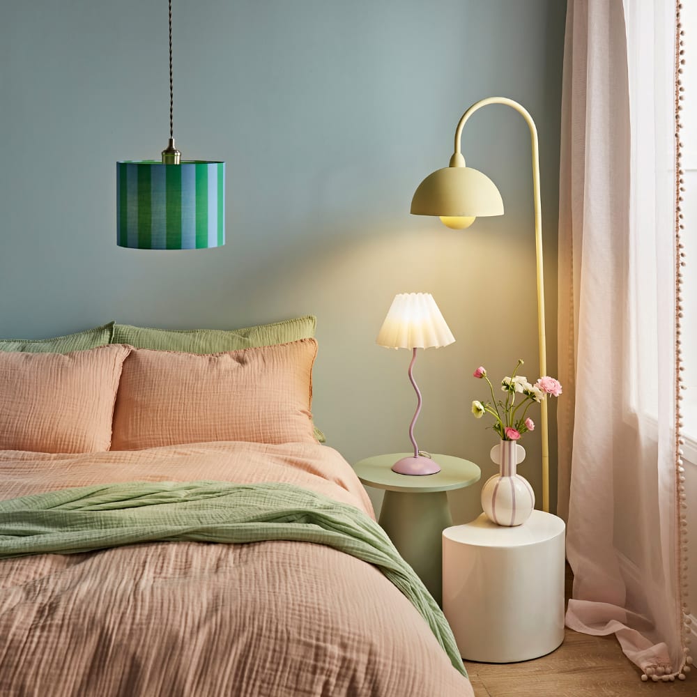 Colourful modern bedroom with pastel pink and green lighting - a playful mix of pendant, table and floor lamps adding warmth and style