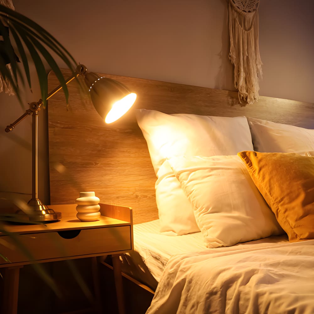 Cosy bedroom with warm brass desk lamp casting a soft golden glow over neutral bedding and wooden headboard for ambient lighting