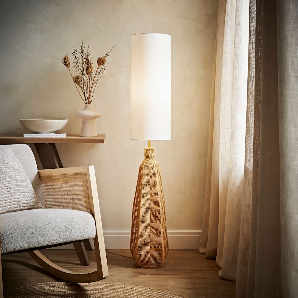 Woven rattan floor lamp with tall white shade styled in a neutral living room corner