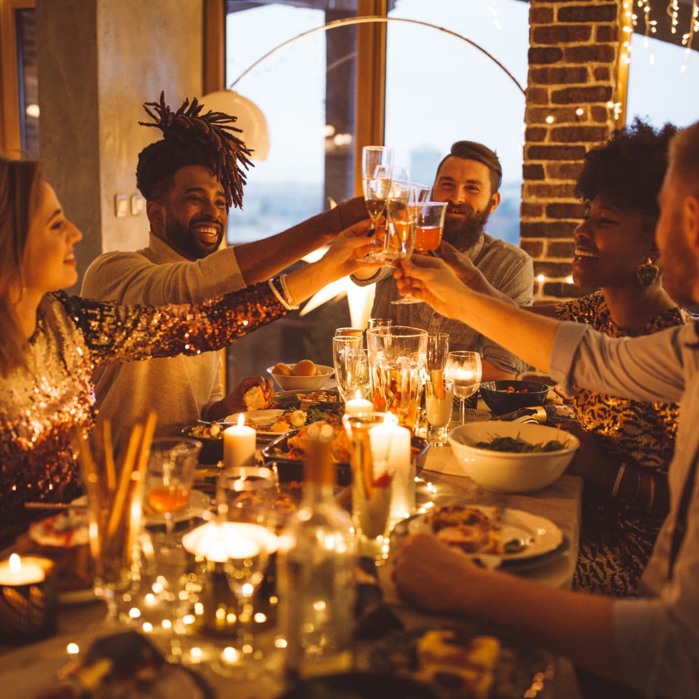 Friends enjoying a festive Christmas dinner with candles, fairy lights, and champagne glasses on a warmly lit dining table, creating a joyful party atmosphere