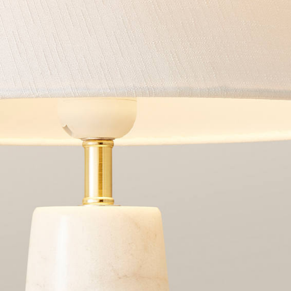 Modern table lamp with a tapered linen shade, gold neck and marble base.
