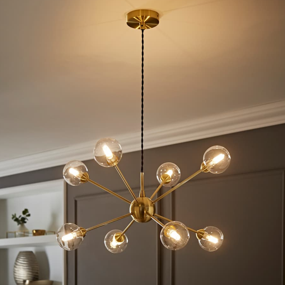 Contemporary gold sputnik chandelier with glowing glass globes, suspended on a braided black fabric cable.